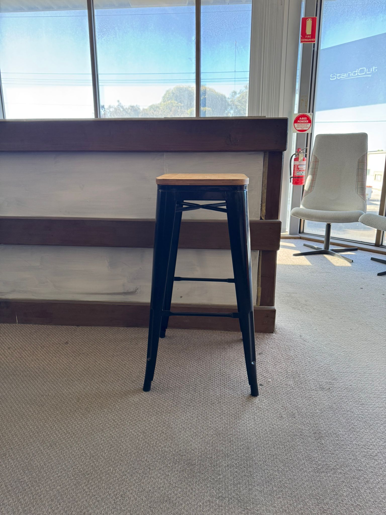 Blue metal bar stool with a wooden seat in an indoor setting.