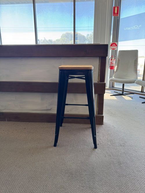 Blue metal bar stool with a wooden seat in an indoor setting.