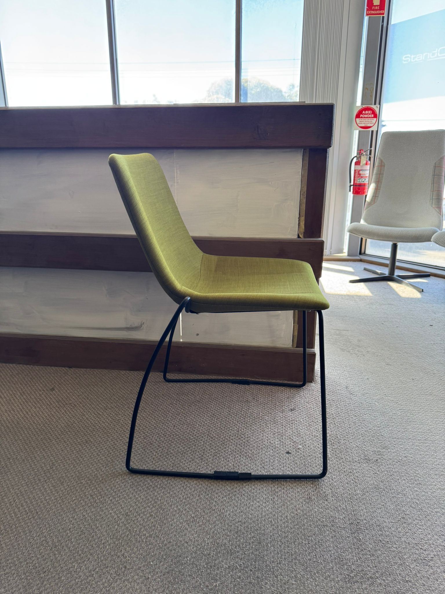 Green chair with black metal legs in a room with large windows