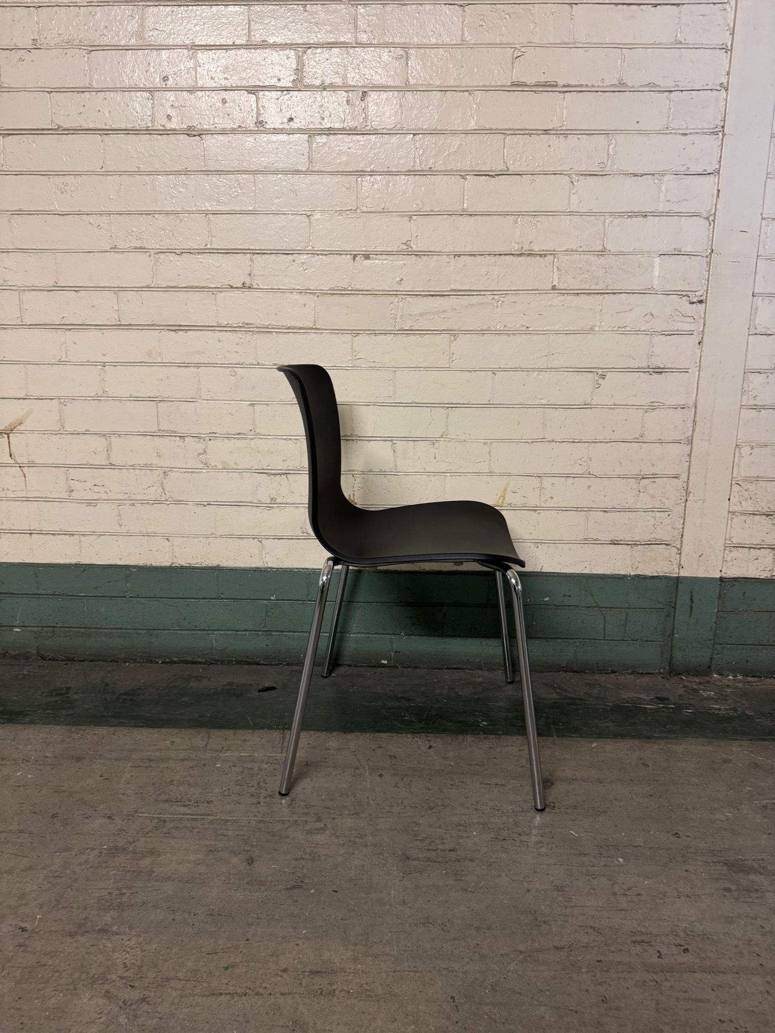 Black chair with metal legs against a white brick wall.