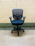 Blue office chair against a beige brick wall.