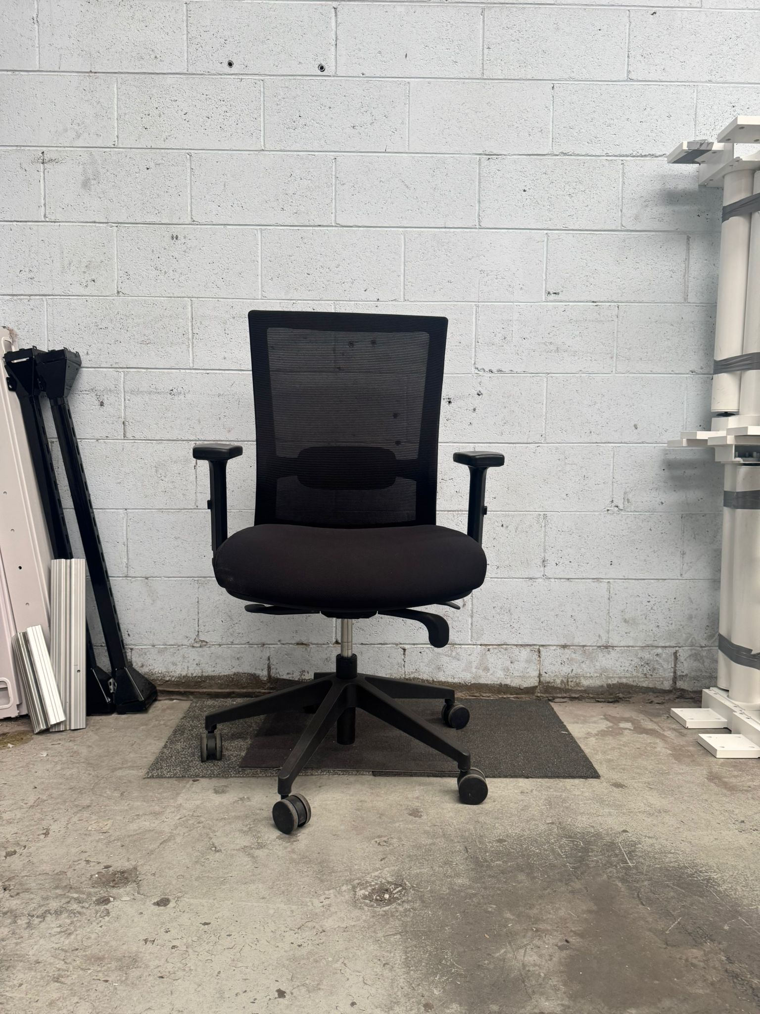 Black office chair in a room with concrete floor and white tiled wall