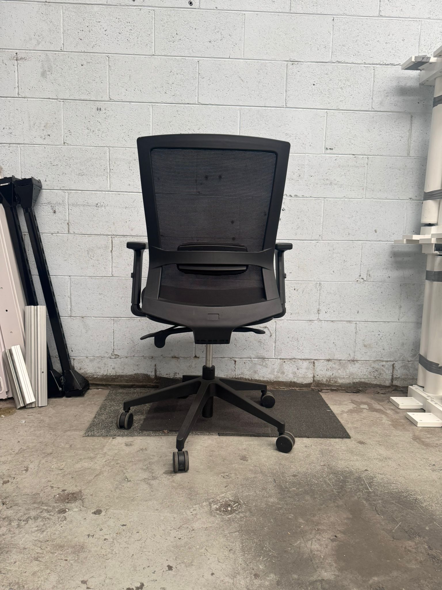Black office chair in a room with concrete floor and white brick wall