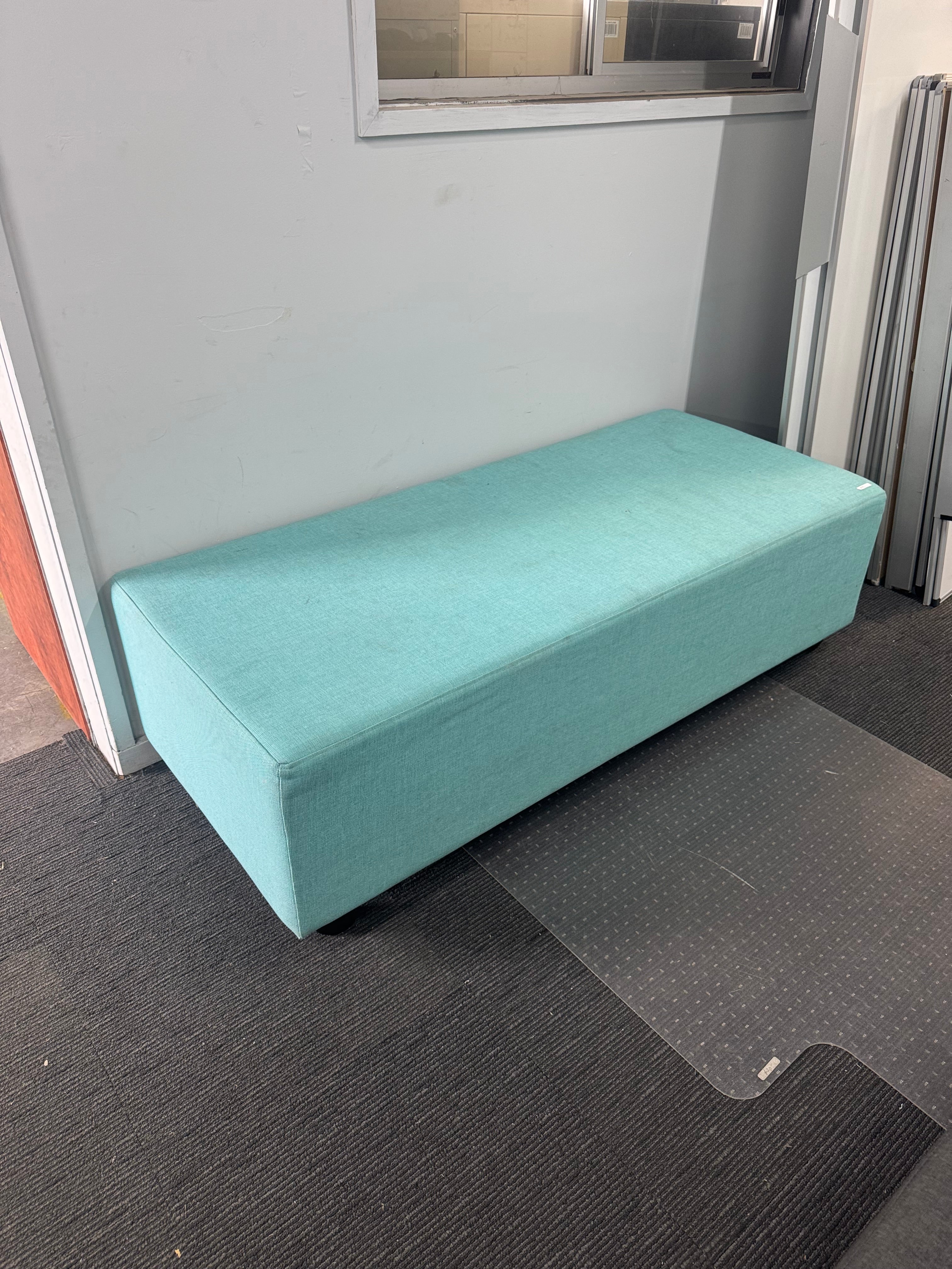 Teal box on a gray surface with a window in the background