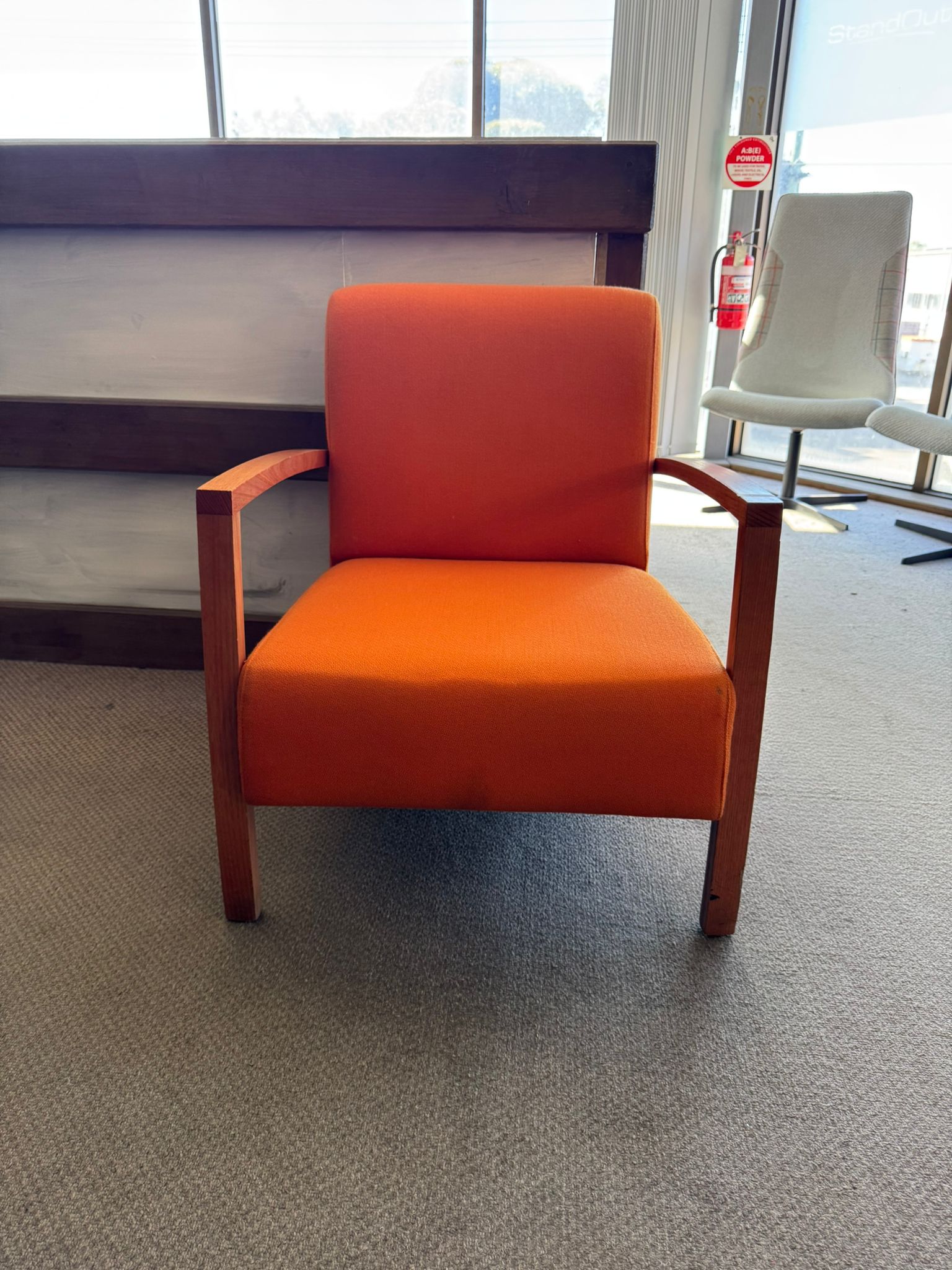 Orange chair with wooden frame in a room with large windows