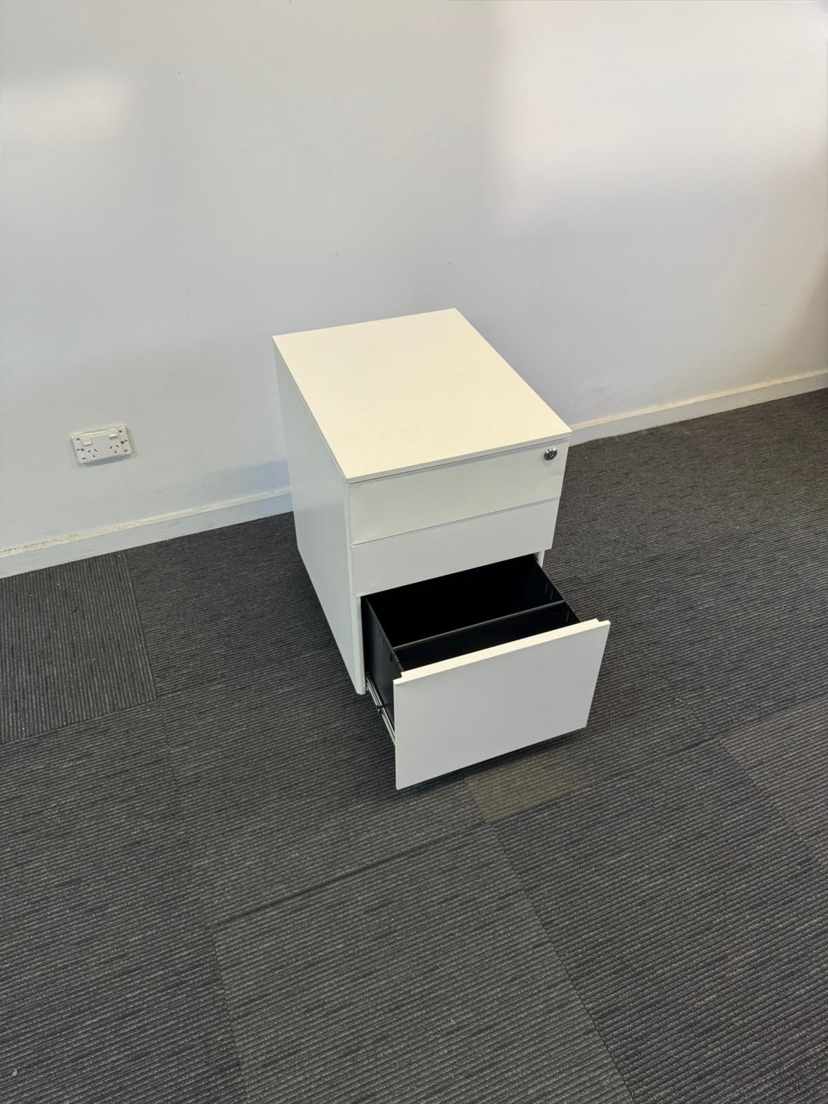 White office cabinet with a drawer open on a gray carpeted floor.