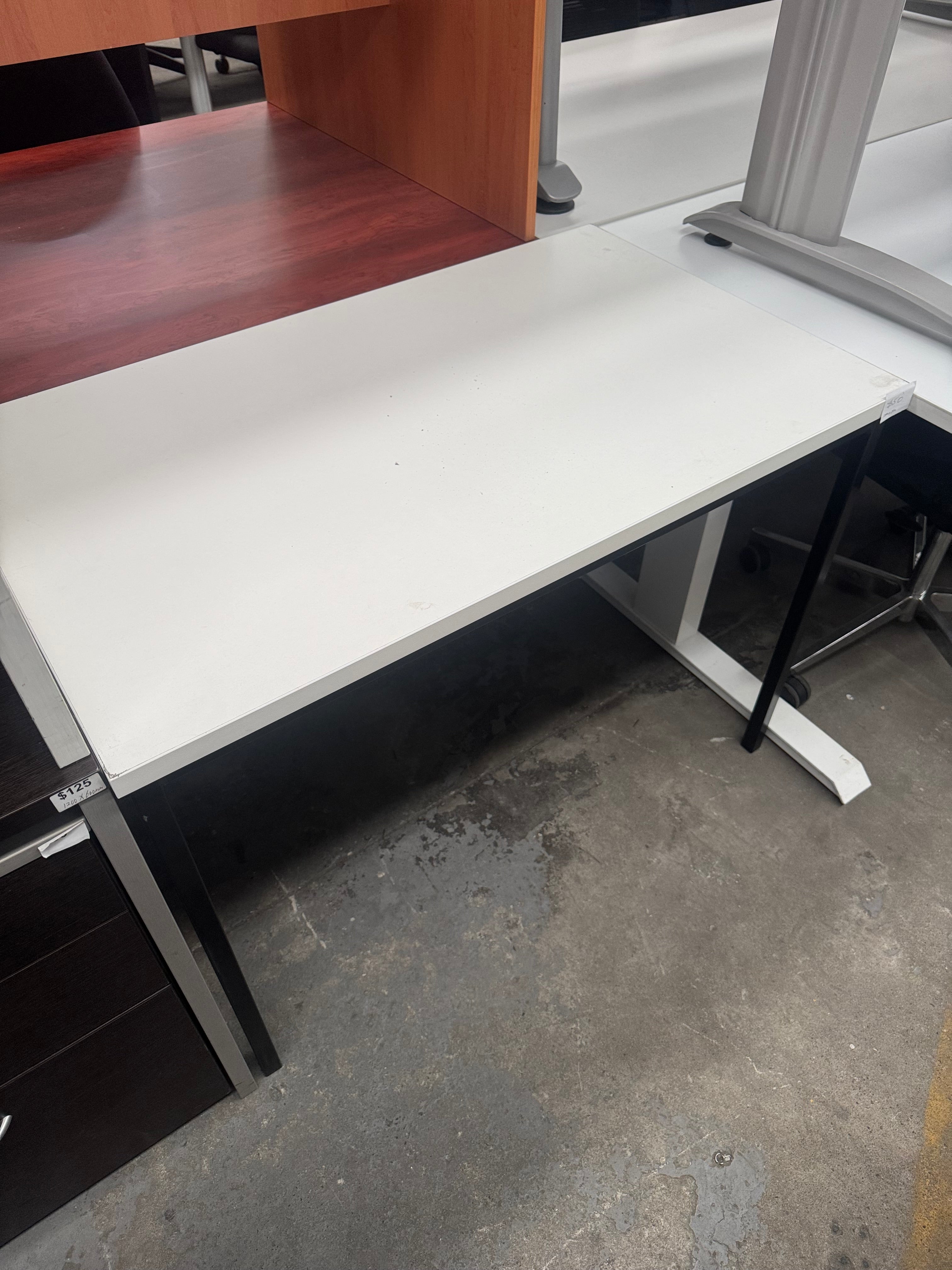 Partial view of a modern office setup with a white desk and wooden chair on a concrete floor.