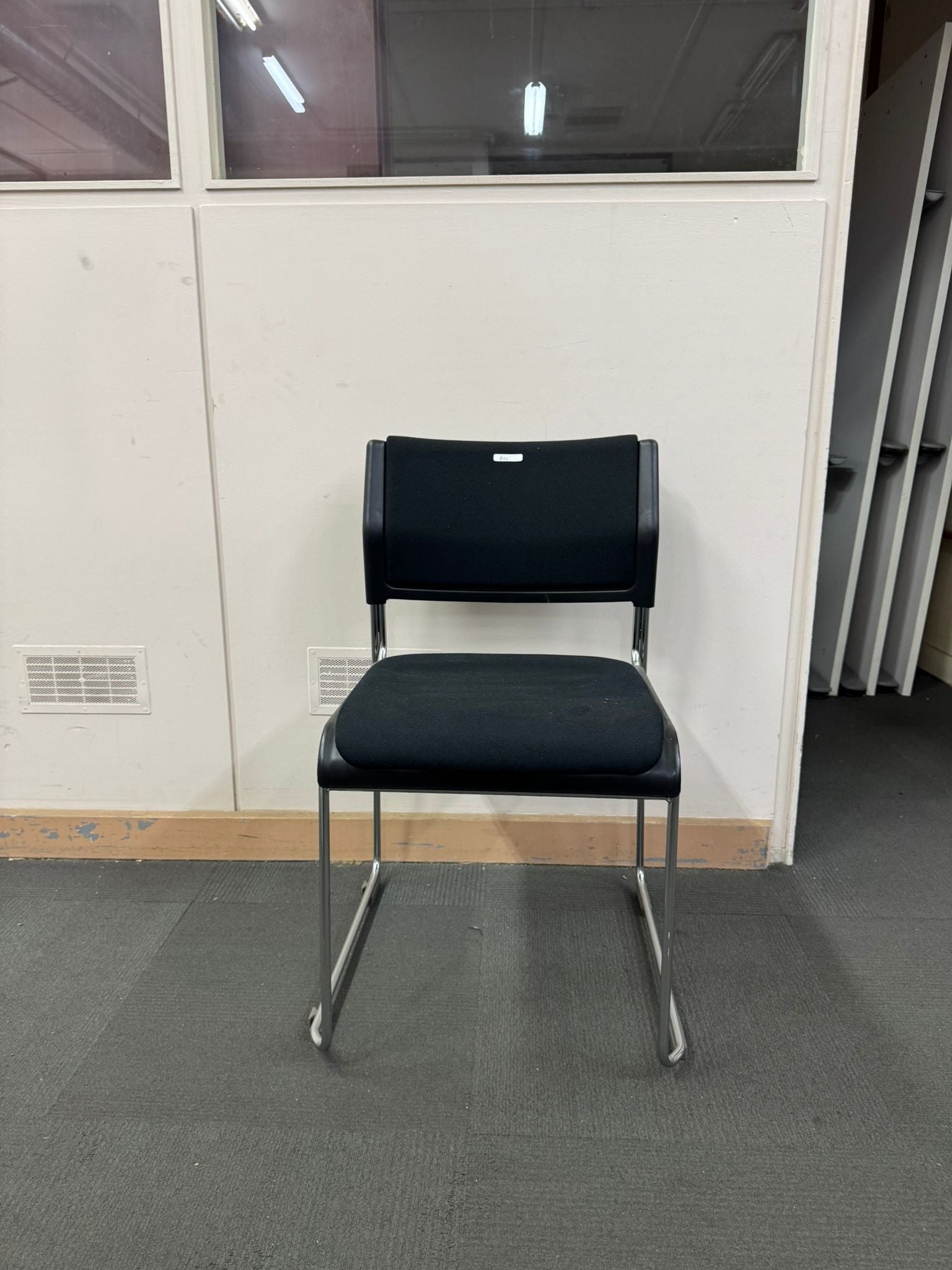 Black office chair in a room with a white wall and gray floor.