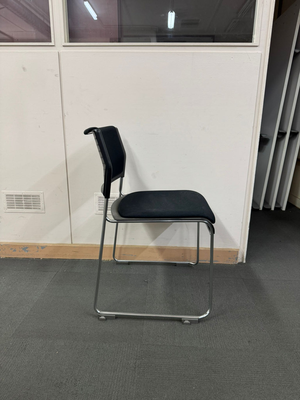 Black chair with metal frame against a white wall.
