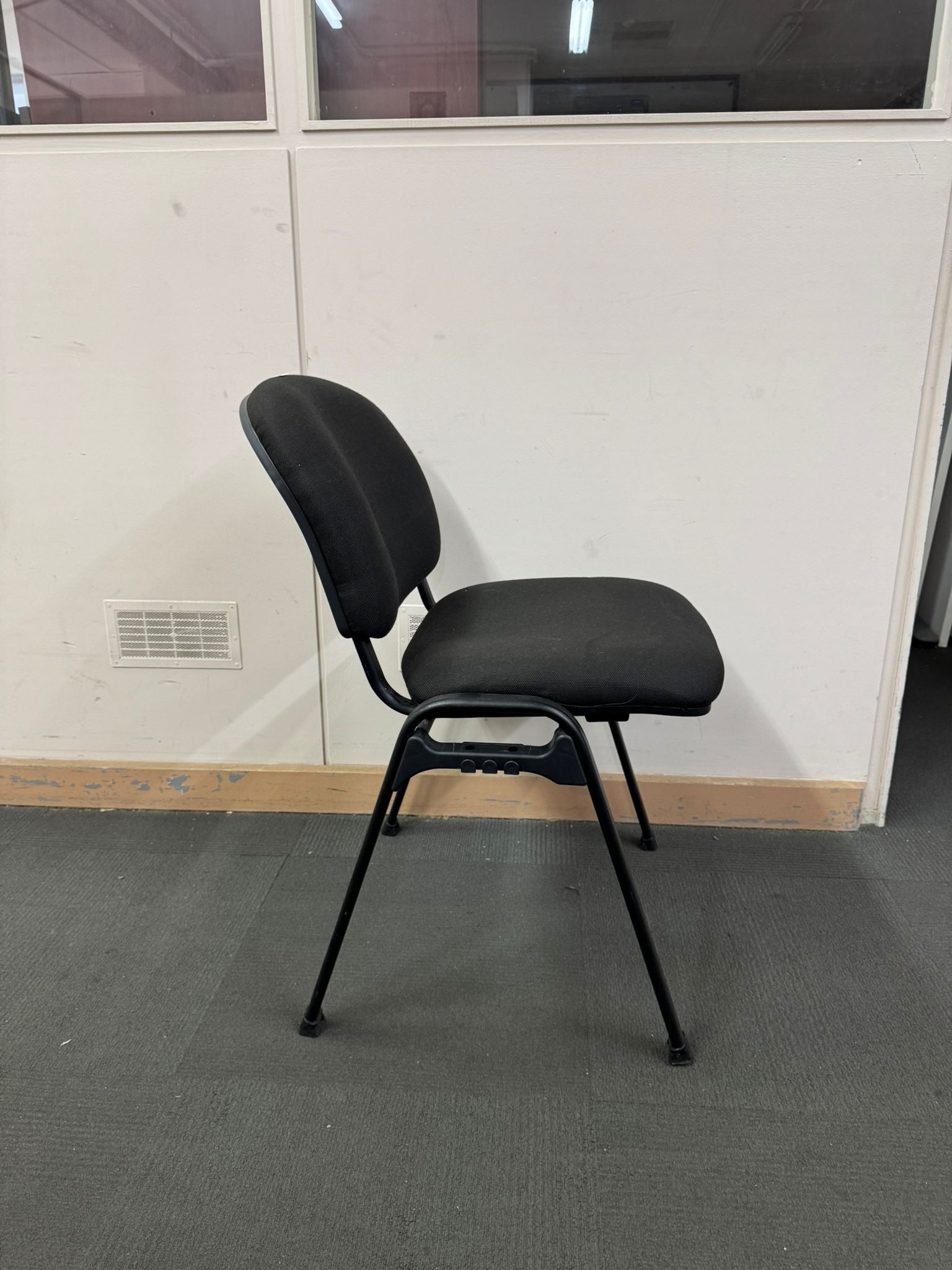 Black office chair against a white wall with a window