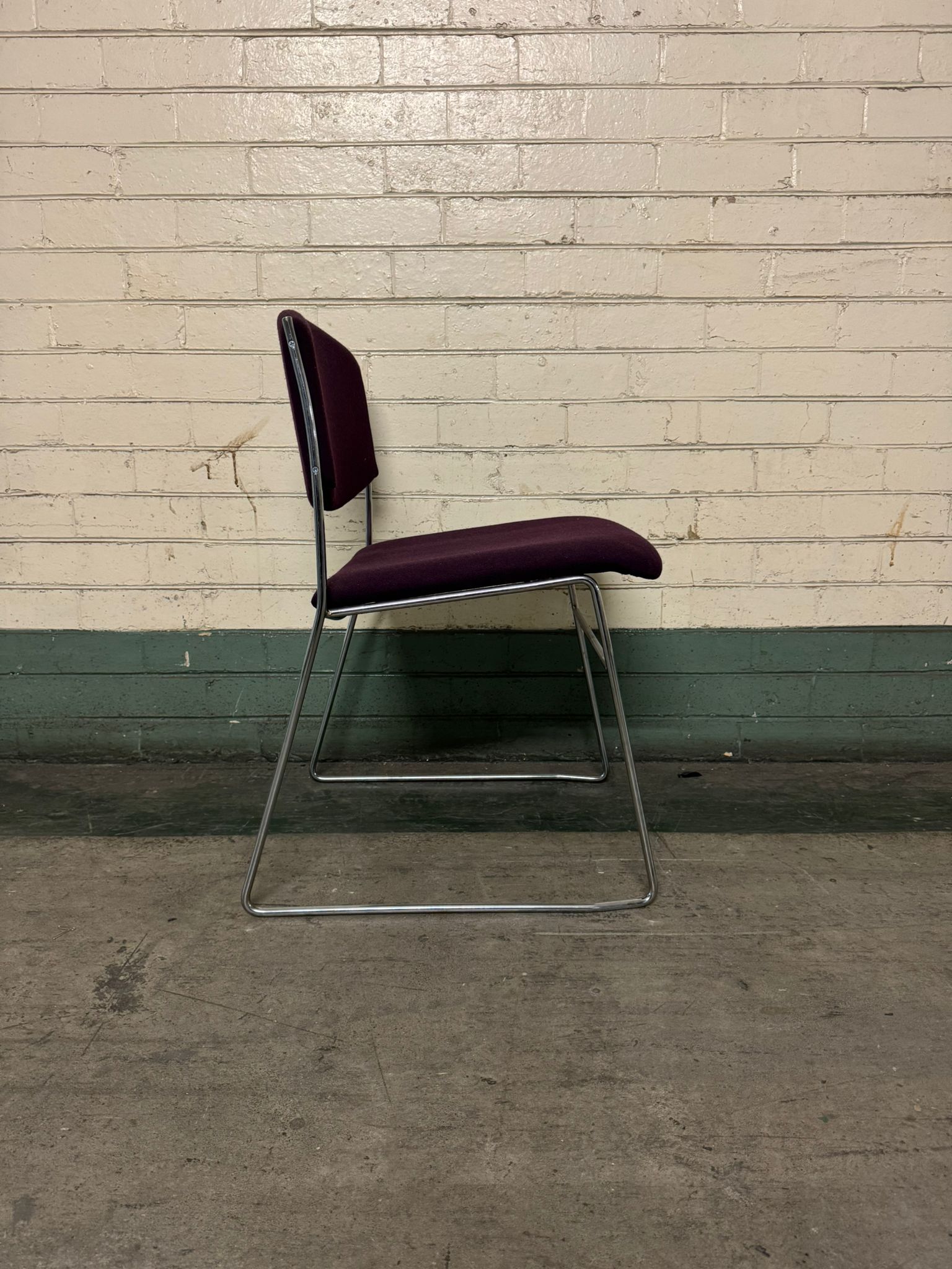 Purple chair with metal legs against a textured wall.