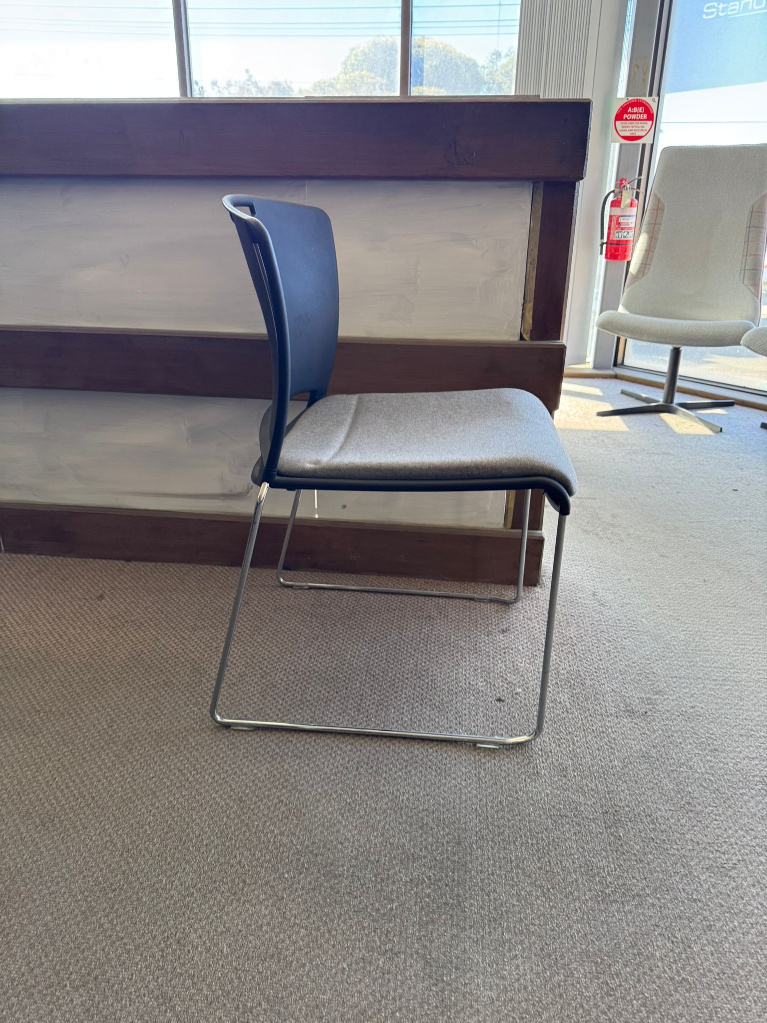 Blue chair with a white cushion on a gray carpeted floor.