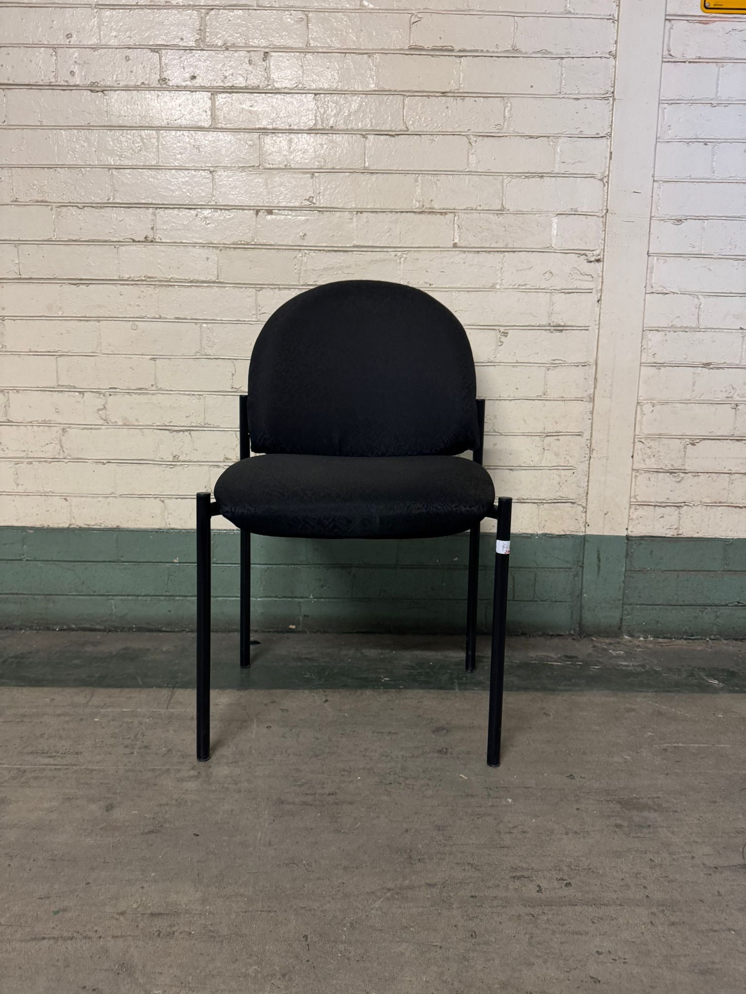Black chair against a white brick wall.