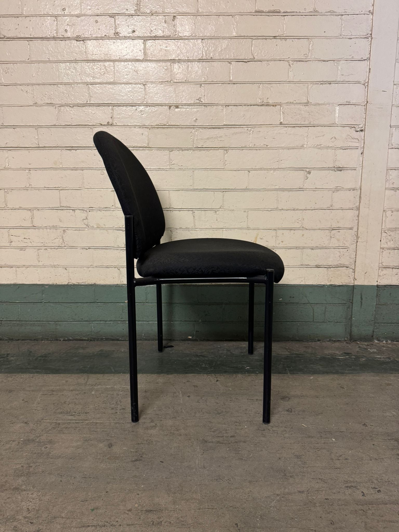 Black chair against a white brick wall.