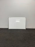A white rectangular dry-erase whiteboard with a silver metal frame, leaning against a plain light gray wall on a dark gray carpeted floor.